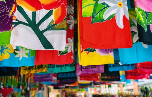 patterned swatches hang from the rafters of a stall in thailand