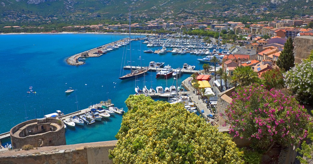 Panorama of Calvi from the citadel with the old tower, pleasure boats, and mountains, Corsica, France