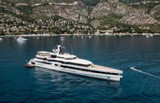 Feadship superyacht lady s underway in cinque terre in italy while on a luxury yacht charter vacation with a fleet of superyachts behind her