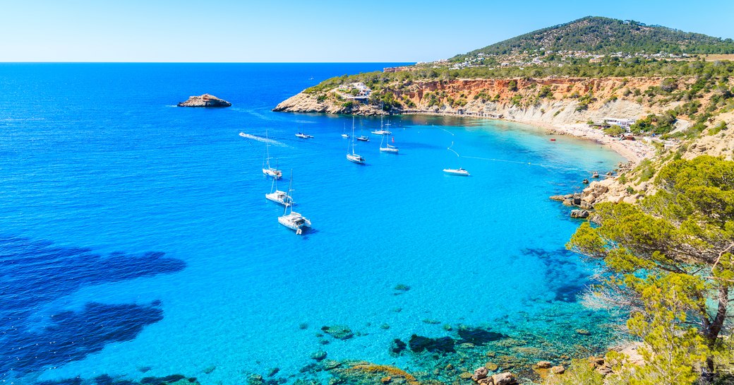 Sailing boats on Cala d'Hort bay with beautiful azure blue sea water, Ibiza island, Spain